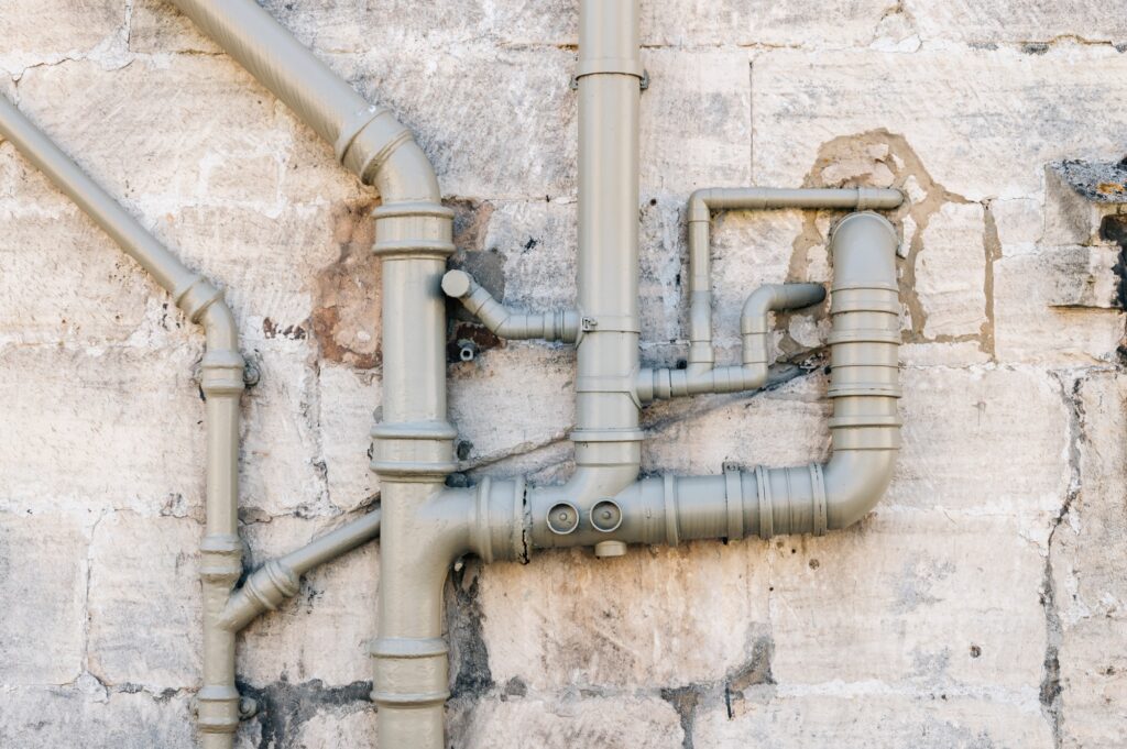 Iron sewer pipes on stone wall background